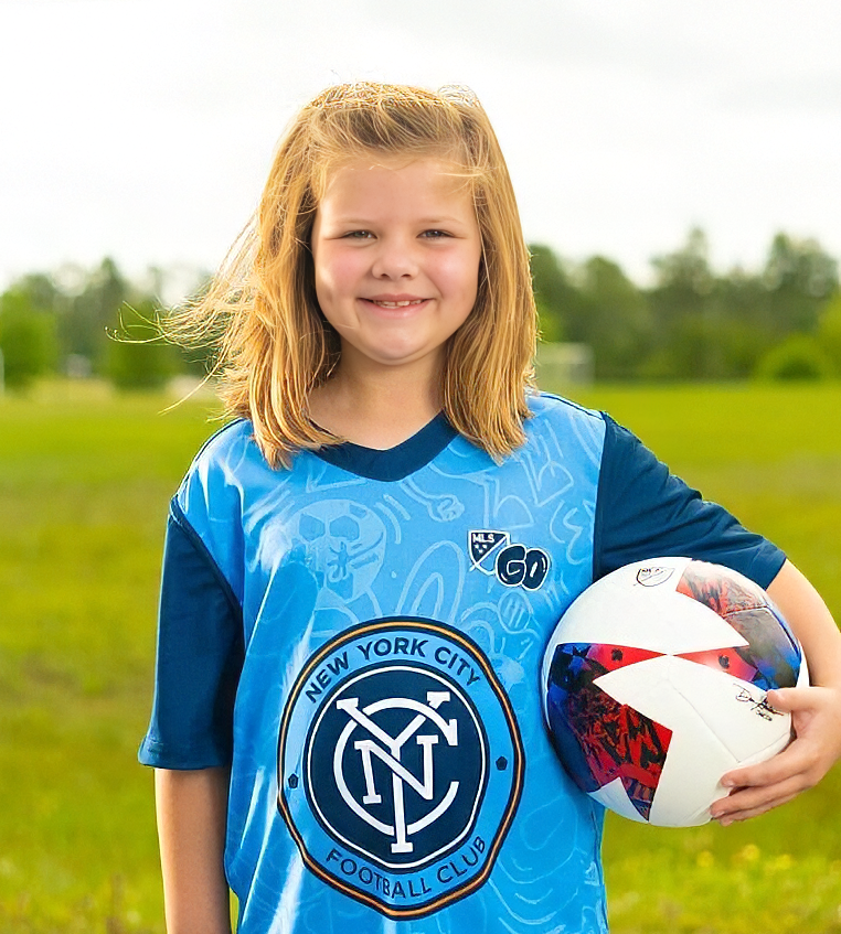 Young MLS GO player in a New York City FC jersey holding a soccer ball